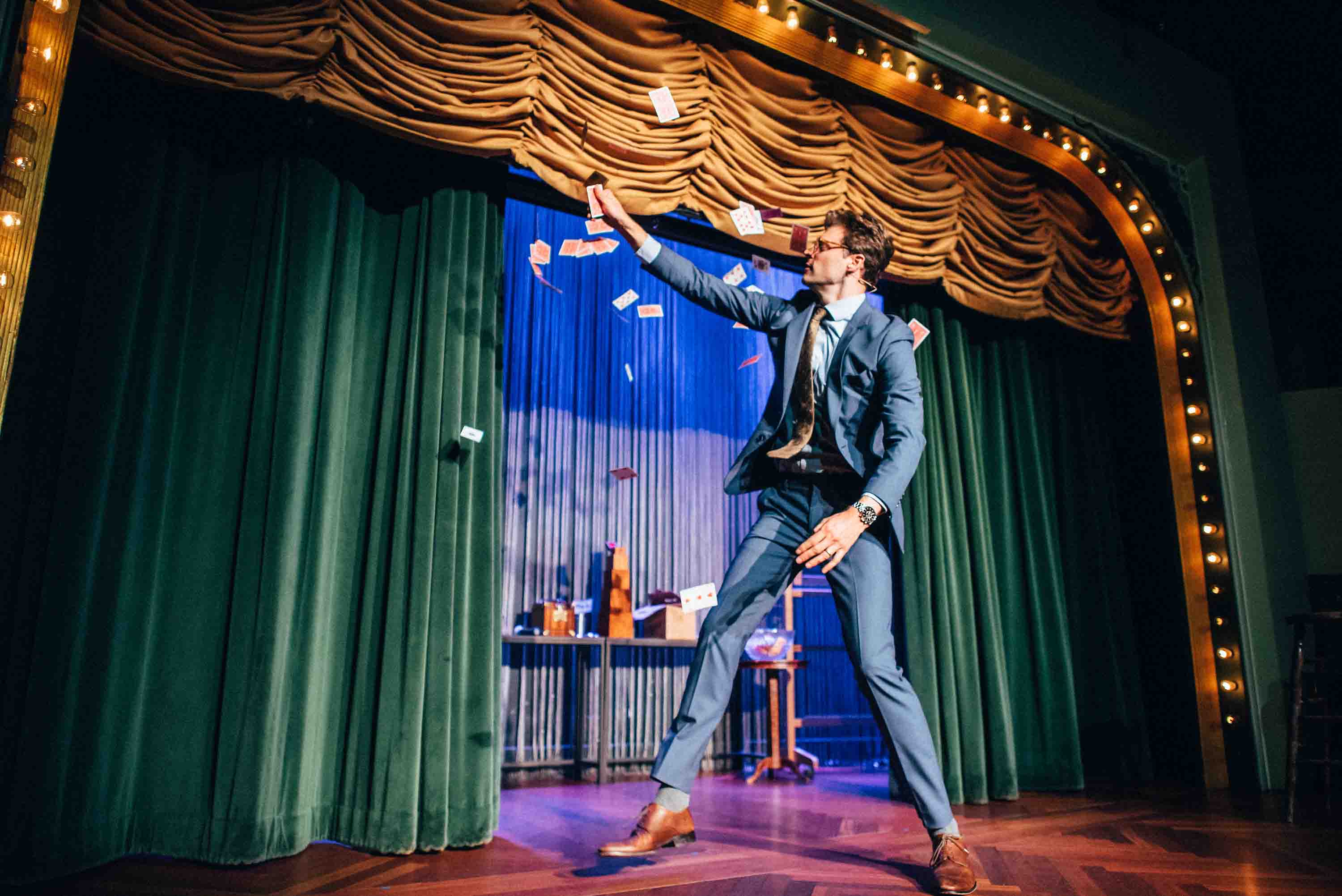 Kevin Blake performing with cards in front of the Palace curtains